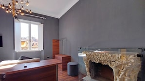 A modern room with a wooden desk, a glass fireplace, and a city view through a large window. - Youroom - Coppelle (Rome)