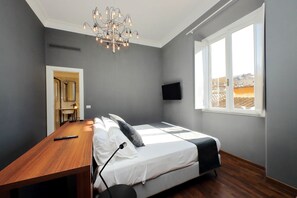 Une chambre à coucher avec un lit, un bureau, une chaise, une télévision et une fenêtre donnant sur un beau paysage.