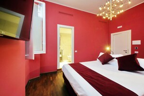A hotel room with a bed, a TV, a door, and a light fixture. - Youroom - Coppelle (Rome)