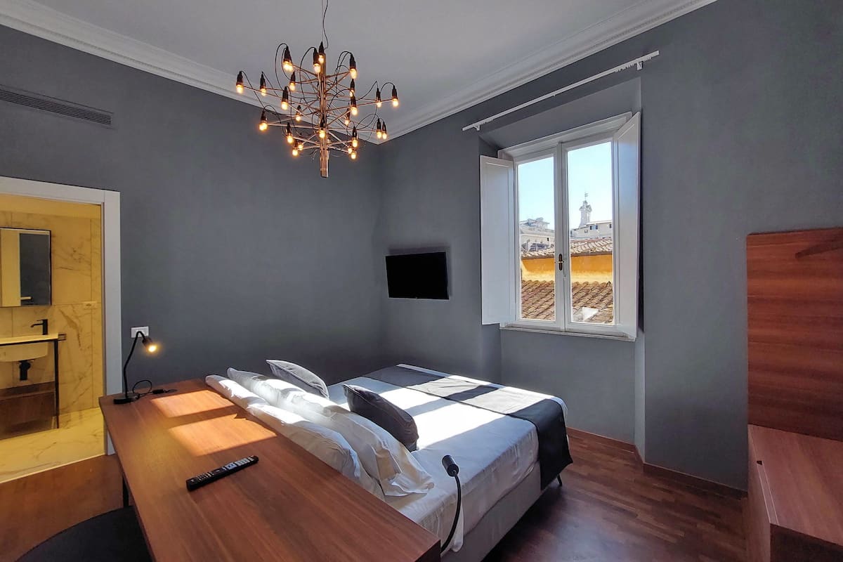 A modern bedroom with a bed, bedside table, and a TV.