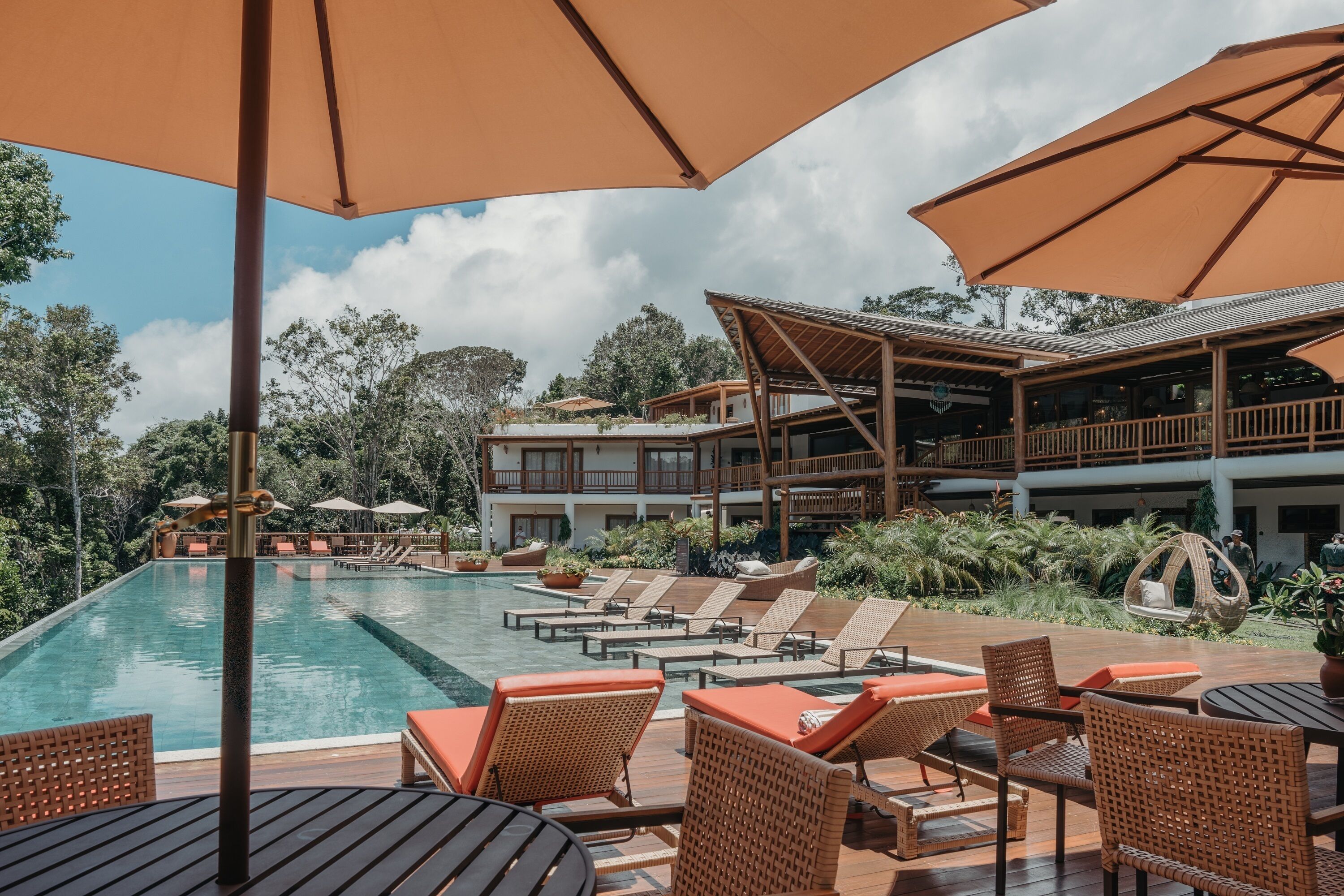 Un espace aménagé au bord de la piscine, avec des chaises longues, des parasols et une terrasse en bois.