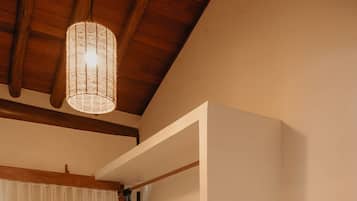 Una habitación con techo de madera, lámpara colgante, pared blanca y cortina blanca.