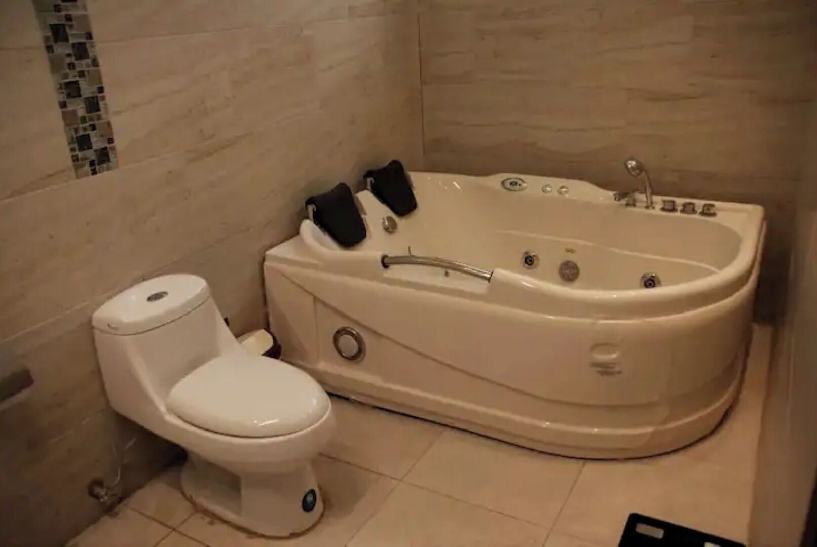 Un baño con inodoro blanco y una bañera grande.