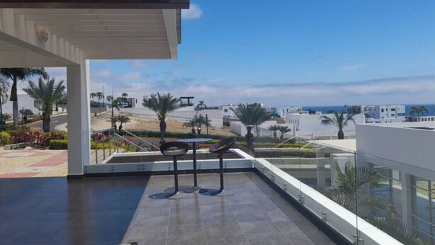 Un edificio moderno con terraza que ofrece vistas a la playa y al paisaje urbano.