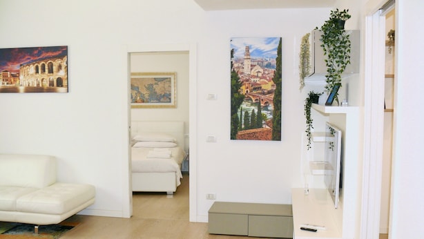 Ein modernes Wohnzimmer mit einem weißen Sofa, einem Bett und Kunstwerken an den Wänden.