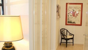Ein Flur mit einer Lampe, einem Stuhl und einem gerahmten Bild an der Wand.