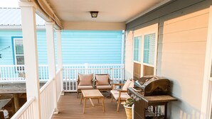 A wooden porch with a railing, two chairs, a table, and a grill. - Rip Line Lodge at Venice Marina- 3bedroom/2bath lodge (Venice)