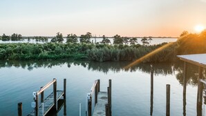 A calm waterfront with a wooden dock extending into the water, surrounded by dense vegetation and trees.