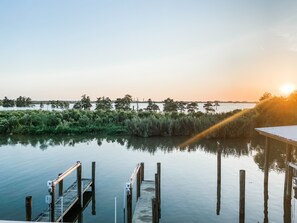 A calm waterfront with a wooden dock extending into the water, surrounded by dense vegetation and trees. - Rip Line Lodge at Venice Marina- 3bedroom/2bath lodge (Venice)