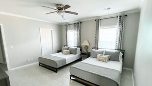 A bedroom with two beds, a ceiling fan, patterned curtains, and a window with blinds. - Rip Line Lodge at Venice Marina- 3bedroom/2bath lodge (Venice)