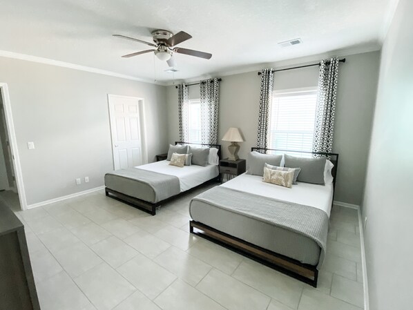 A bedroom with two beds, a ceiling fan, patterned curtains, and a window with blinds. - Rip Line Lodge at Venice Marina- 3bedroom/2bath lodge (Venice)