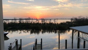 A waterfront view with a dock and a pier extending into calm water, surrounded by marsh vegetation. - Rip Line Lodge at Venice Marina- 3bedroom/2bath lodge (Venice)