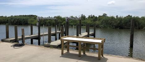A concrete dock with a wooden bench and a metal railing.