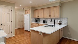 A modern kitchen with wooden cabinets, a white countertop, a built-in sink, and a refrigerator. - Pinehurst No. 6 Golf Front Getaway (Pinehurst)