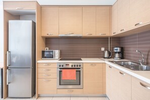 A modern kitchen with a stainless steel refrigerator, a microwave, a toaster, a coffee maker, and a built-in oven. - Elegant Home with Balcony by CloudKeys (Athens)