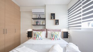 A neatly arranged bedroom with a bed, bedside tables, a wardrobe, and a window with blinds.