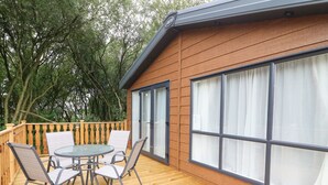 Una terraza de madera con un ventanal de vidrio que da a una habitación.