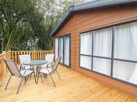A wooden deck with a glass door leading to a room.