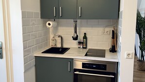 A compact kitchen with grey cabinets, a stainless steel dishwasher, and a built-in oven. - Sweet Spot | Studio apartment close to the city center (Trierweiler)