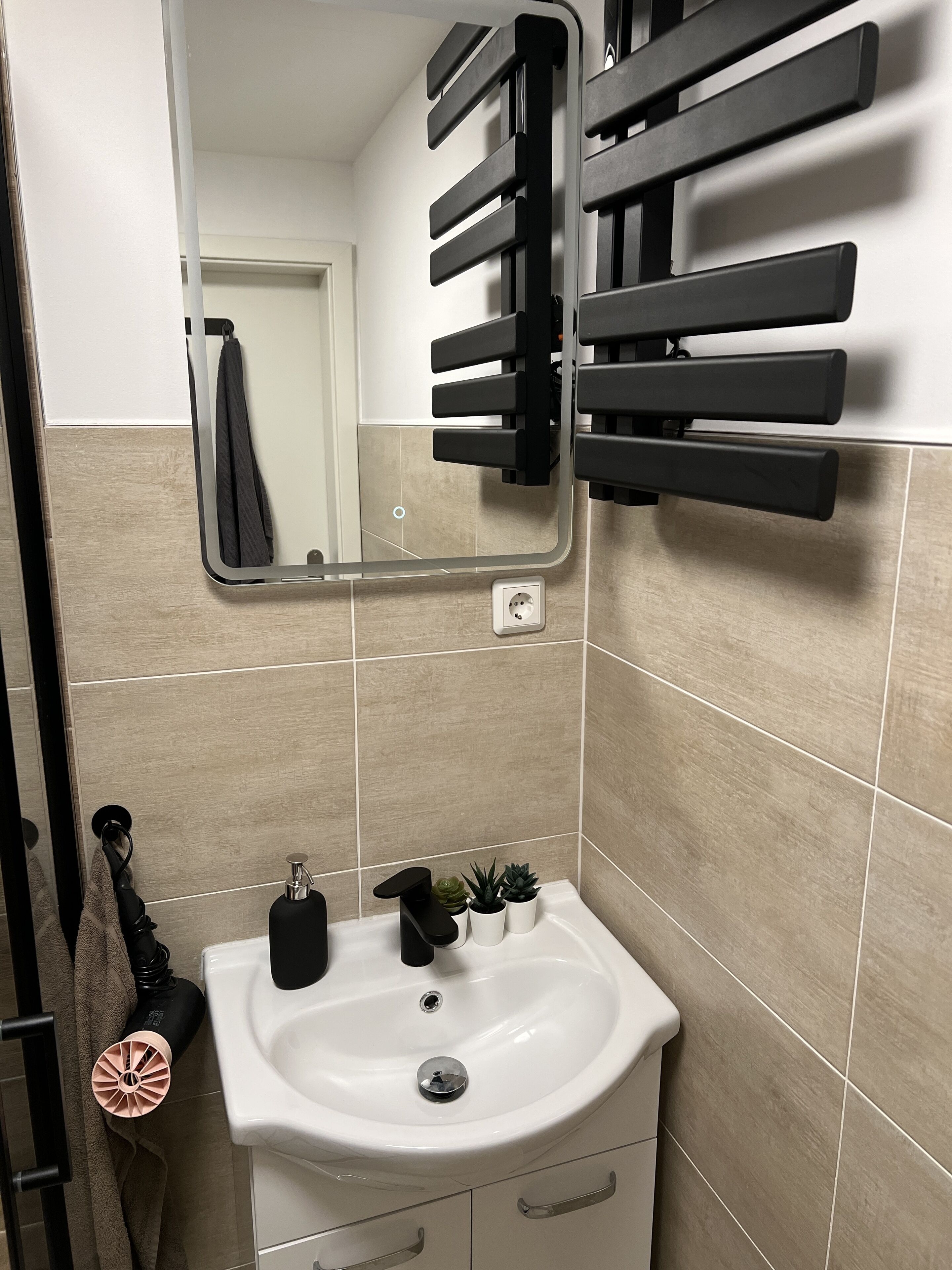 Een badkamer met een wit wastafel, een spiegel en een handdoekhouder.