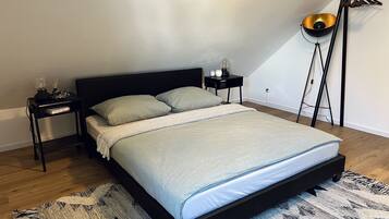 A modern bedroom with a bed, a nightstand, a lamp, and a hanging light fixture.