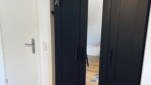 A closed black wardrobe with a mirror, a white door, and a wooden floor. - Sweet Spot | Studio apartment close to the city center (Trierweiler)