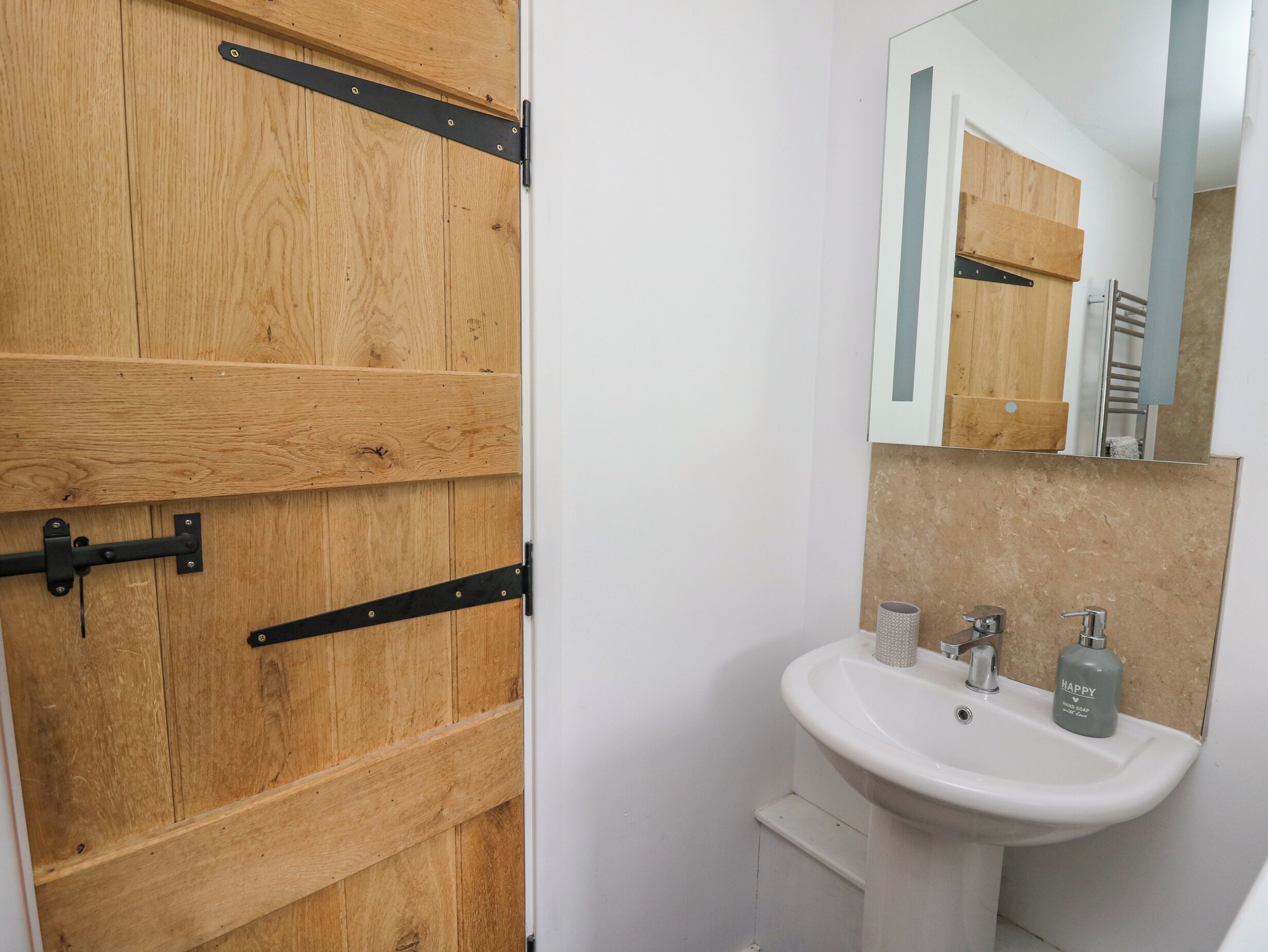 A bathroom with a wooden door, a white sink, and a mirror.
