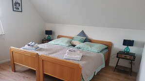 Ett sovrum med en säng i trä, två sängbord, en mjuk matta och en inramad tavla på väggen.