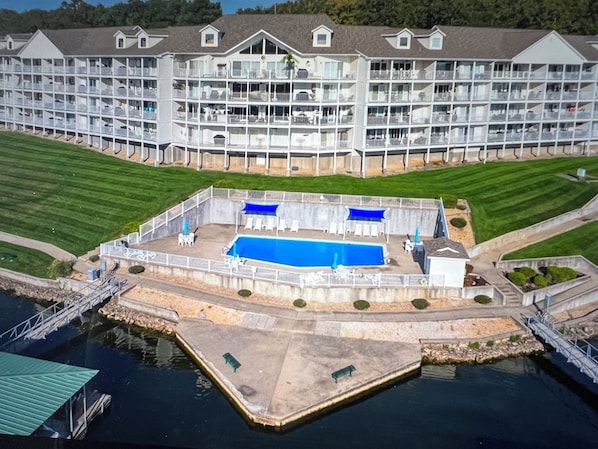 A large hotel with multiple balconies, a swimming pool, and a well-maintained lawn. - Beautiful lake front condo in perfect location by land and water. Boat Slip. (Osage Beach)
