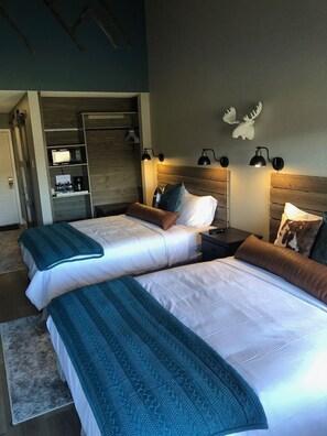 Ett hotellrum med två sängar, en garderob, ett skrivbord och en vägglampa.