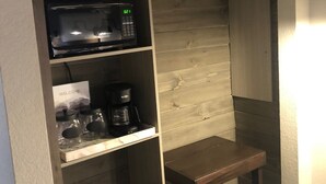 Une petite cuisine équipée d’un four à micro-ondes, d’une machine à café et de bocaux de rangement.