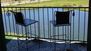 Un balcon avec deux chaises donnant sur un lac et offrant une vue sur un quartier résidentiel.