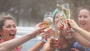 Un groupe de personnes trinquant avec des coupes de champagne dans un jacuzzi.