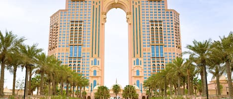 Un gran hotel con un arco llamativo y una larga piscina con detalles decorativos.