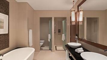 Une salle de bain moderne avec une baignoire, deux lavabos, un grand miroir et un espace douche.