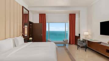 Ein Hotelzimmer mit Bett, Schreibtisch, Stuhl, Fernseher und Meerblick.