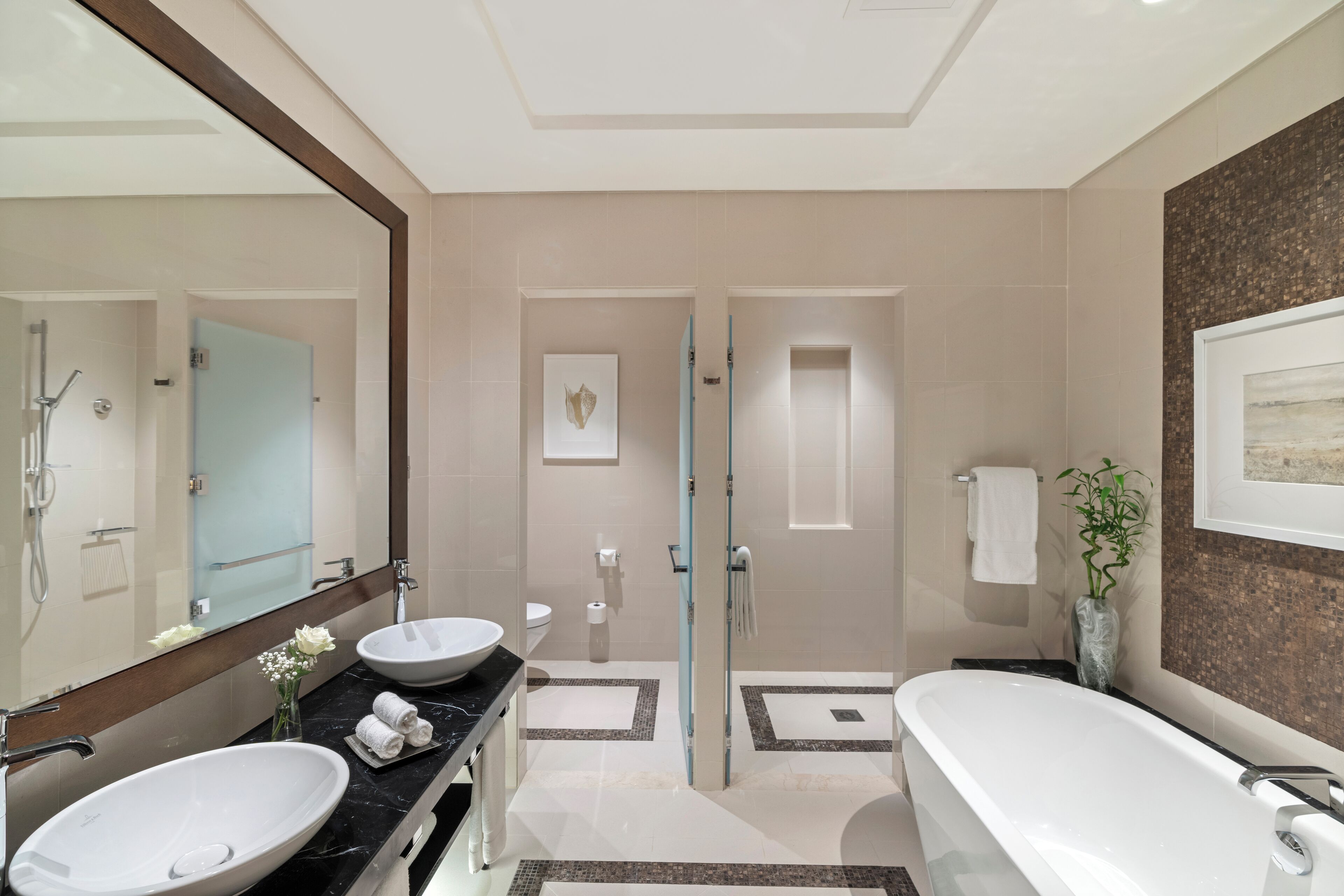 Un baño moderno con una bañera grande, dos lavamanos, una cabina de ducha de vidrio y un espejo amplio.