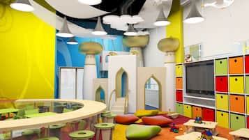 Children can play and relax in this vibrant play area with tables, bean bags, and a large TV.