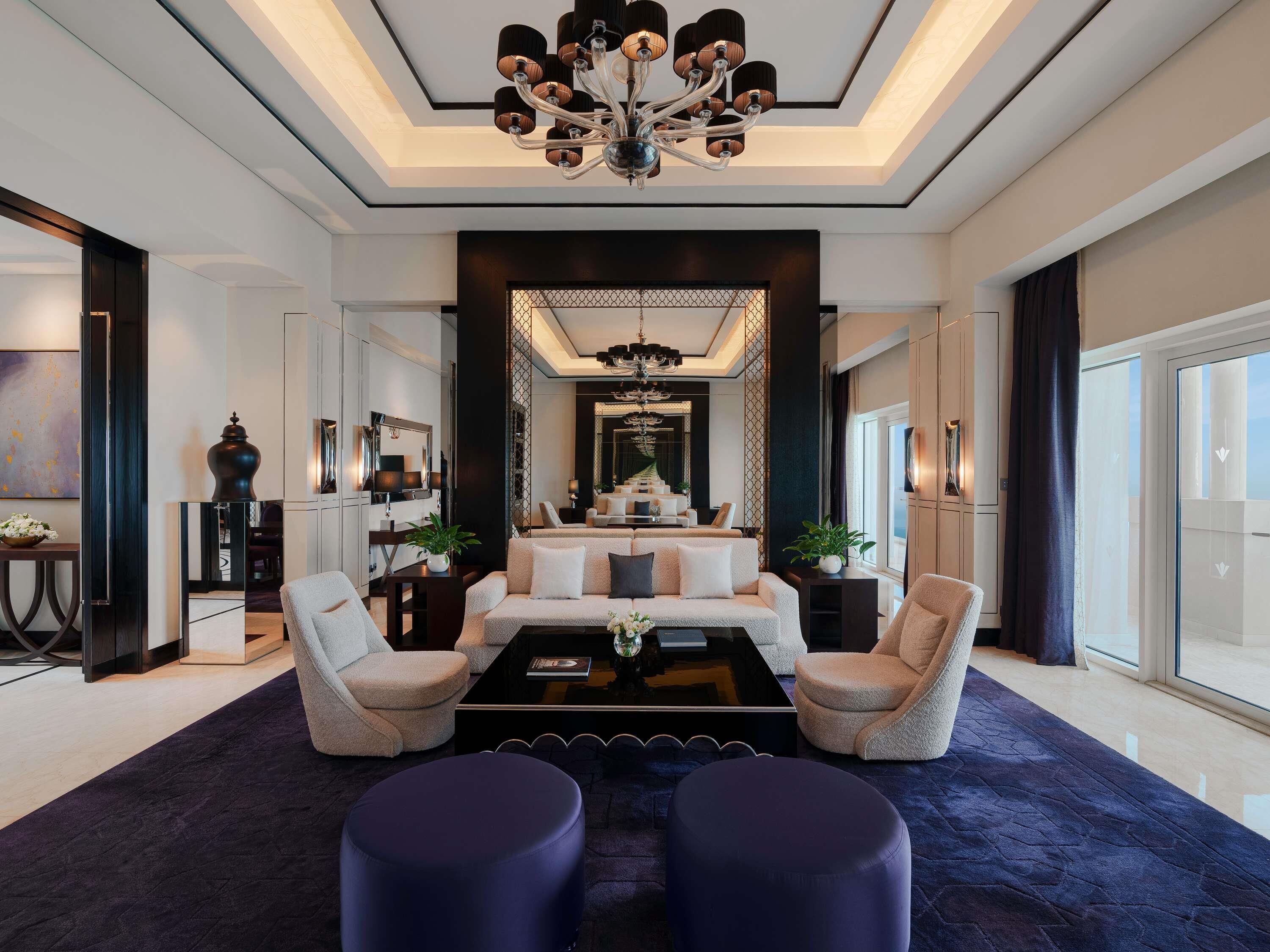 A modern living room with a central sofa, two armchairs, a coffee table, and a chandelier.