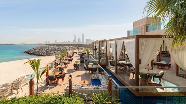 A rooftop bar with a pool, overlooking a beach and city skyline. - Rixos Marina Abu Dhabi (Abu Dhabi)
