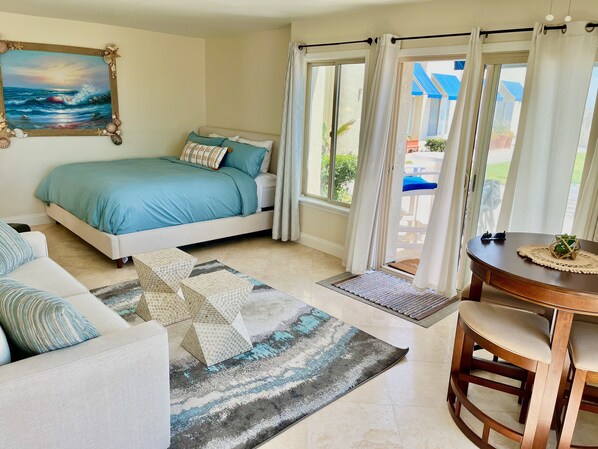 Quarto com cama, sofá, mesa de jantar e vista para o exterior.