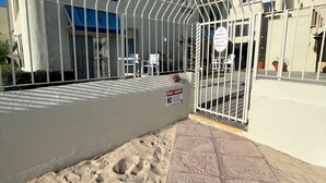 Un ingresso recintato a un edificio con un tendone blu, un cartello che indica divieto di accesso e un avviso di videosorveglianza.