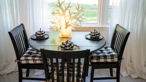 A dining table with four chairs, each with a checkered cushion. A decorative coral centerpiece is on the table. - Firefly Cottage at the Cape, Hot Tub, Community beach, Boat Show, USNA Football. (Annapolis)