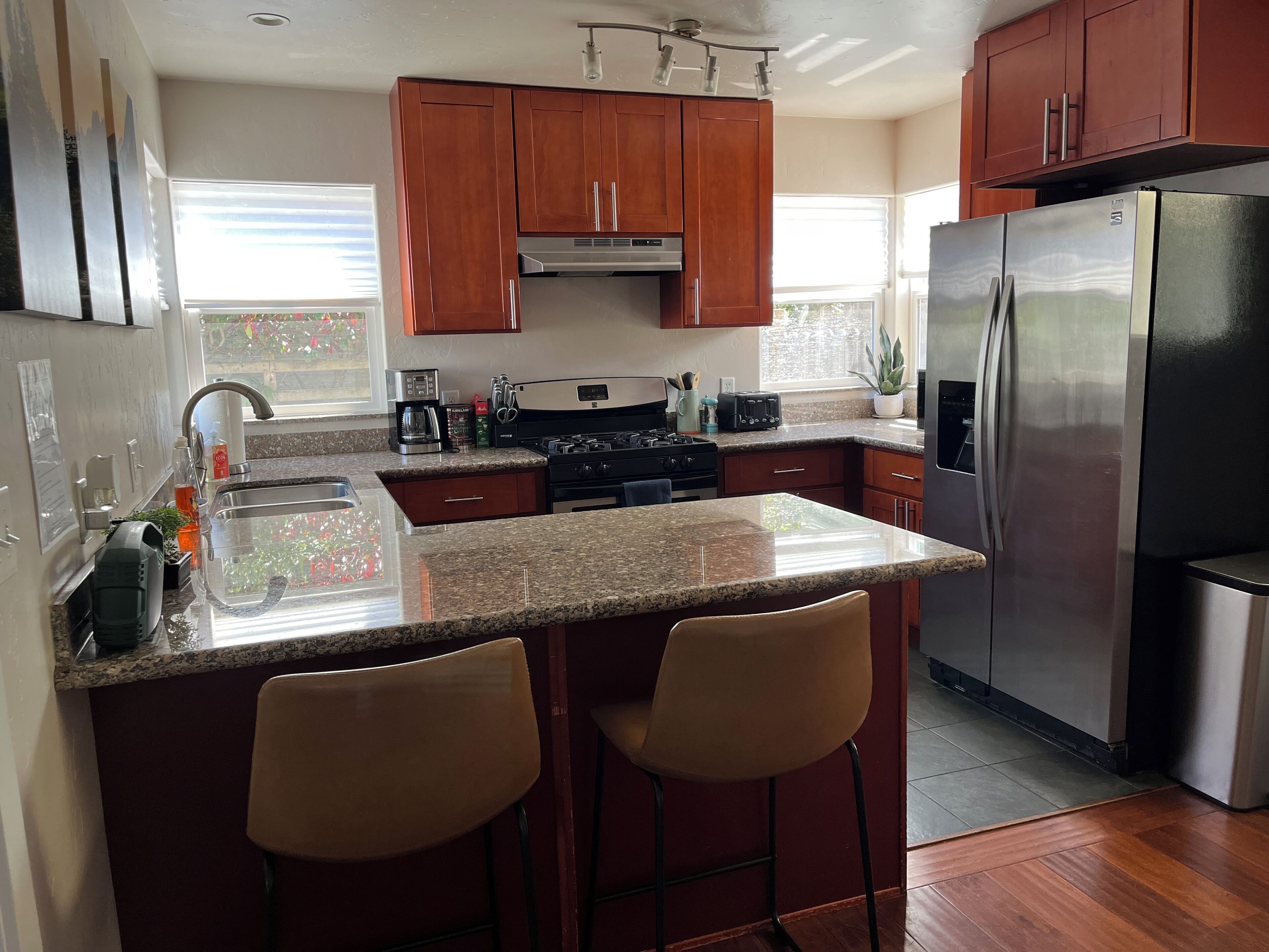 Una cocina con armarios de madera, un refrigerador de acero inoxidable, una estufa a gas y una encimera de granito.