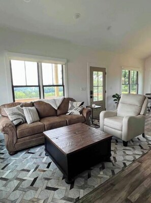 Relax in this stylish living room with a large window, comfortable sofa, and armchair.
