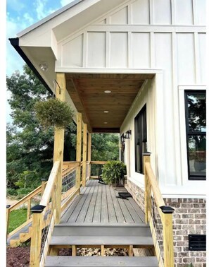 Leading to a charming building with a brick foundation, this outdoor space offers a wooden railing and outdoor lighting.