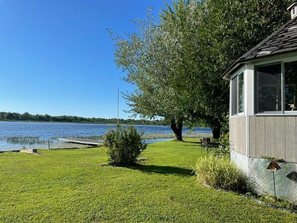 A lakeside property with a dock, a grassy lawn, and a building with large windows.