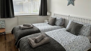 Un dormitorio con dos camas, un adorno con forma de estrella en la pared y una ventana con cortinas.