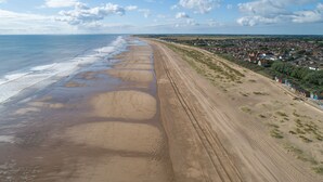Una carretera costera con una playa a un lado y una zona residencial al otro.