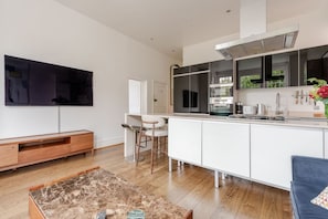 A modern kitchen with a large island, built-in appliances, and a dining area with bar stools. - Luxury Central London 2 x double bed apartment - Hampstead (London)